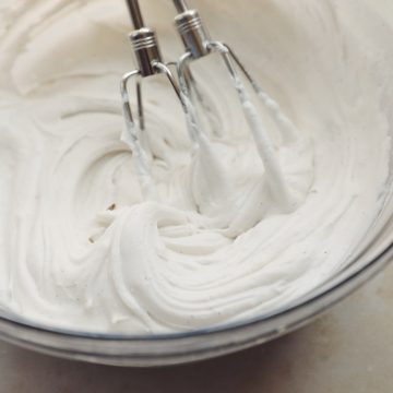 a glass bowl with coconut whipping cream in it and the beaters from a hand mixer