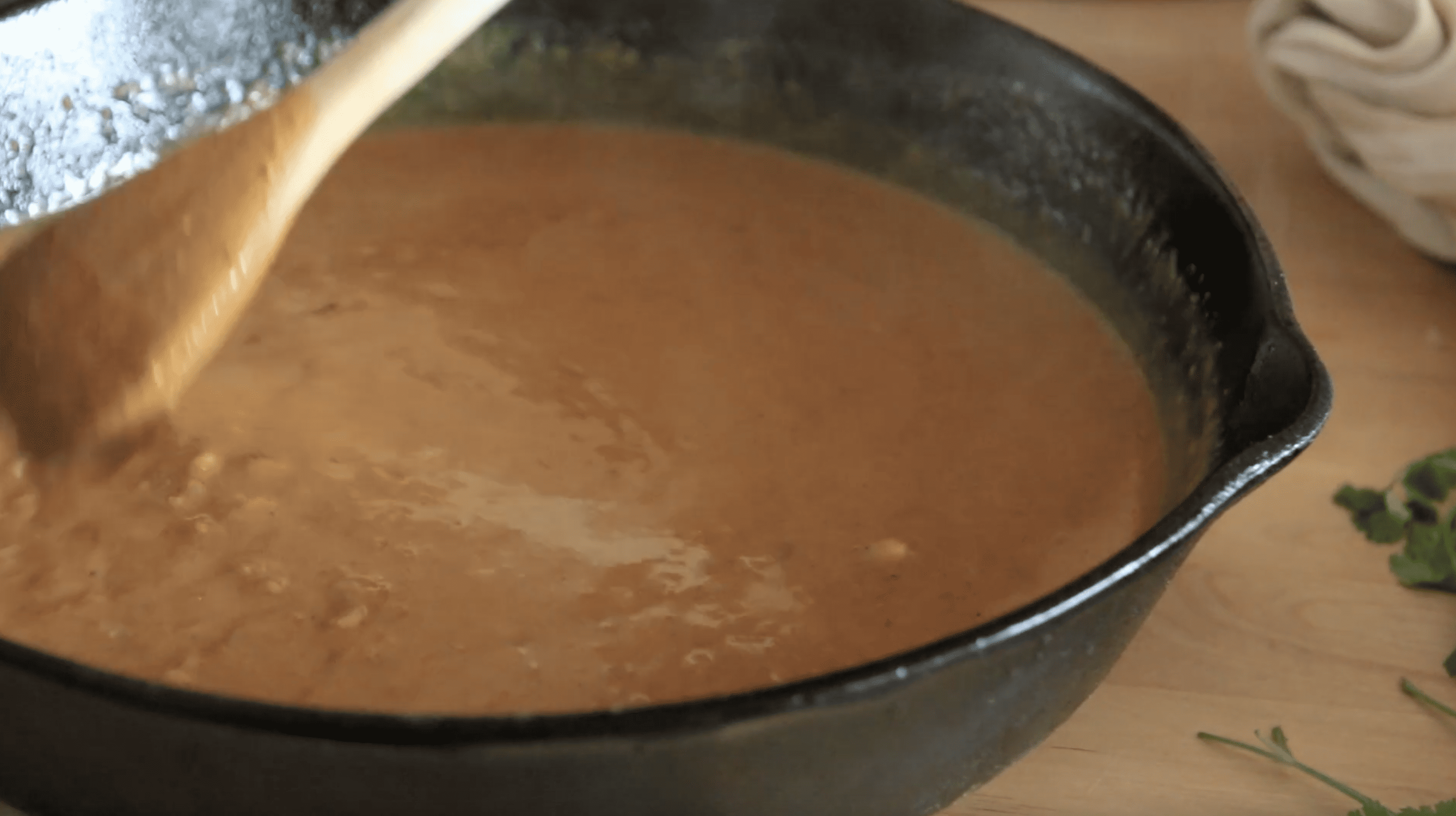 pan with a spoon stirring butter chicken sauce