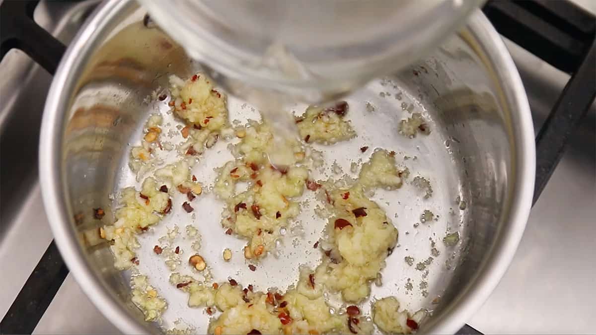 sauce pan with garlic, ginger and chili being cooked
