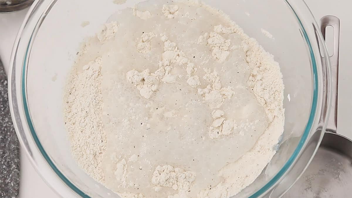 flour batter with water being added in a mixing bowl