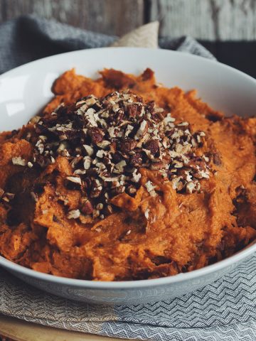 bowl of sweet potato mash topped with pecans