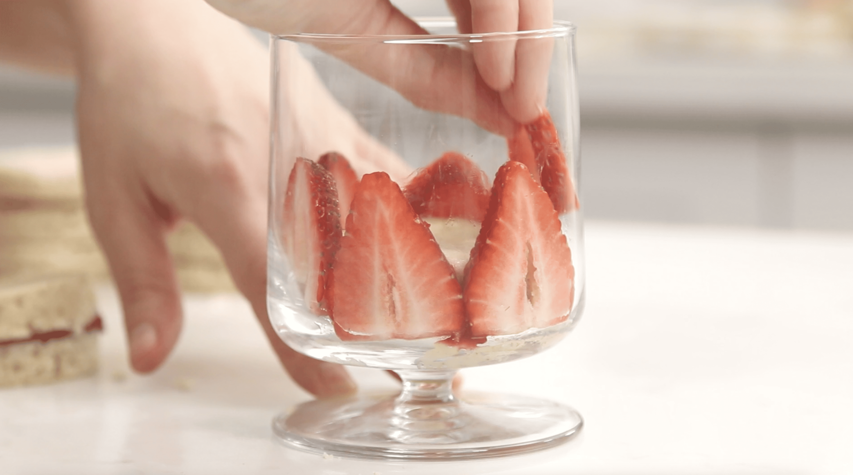 strawberry slices being placed around a glass