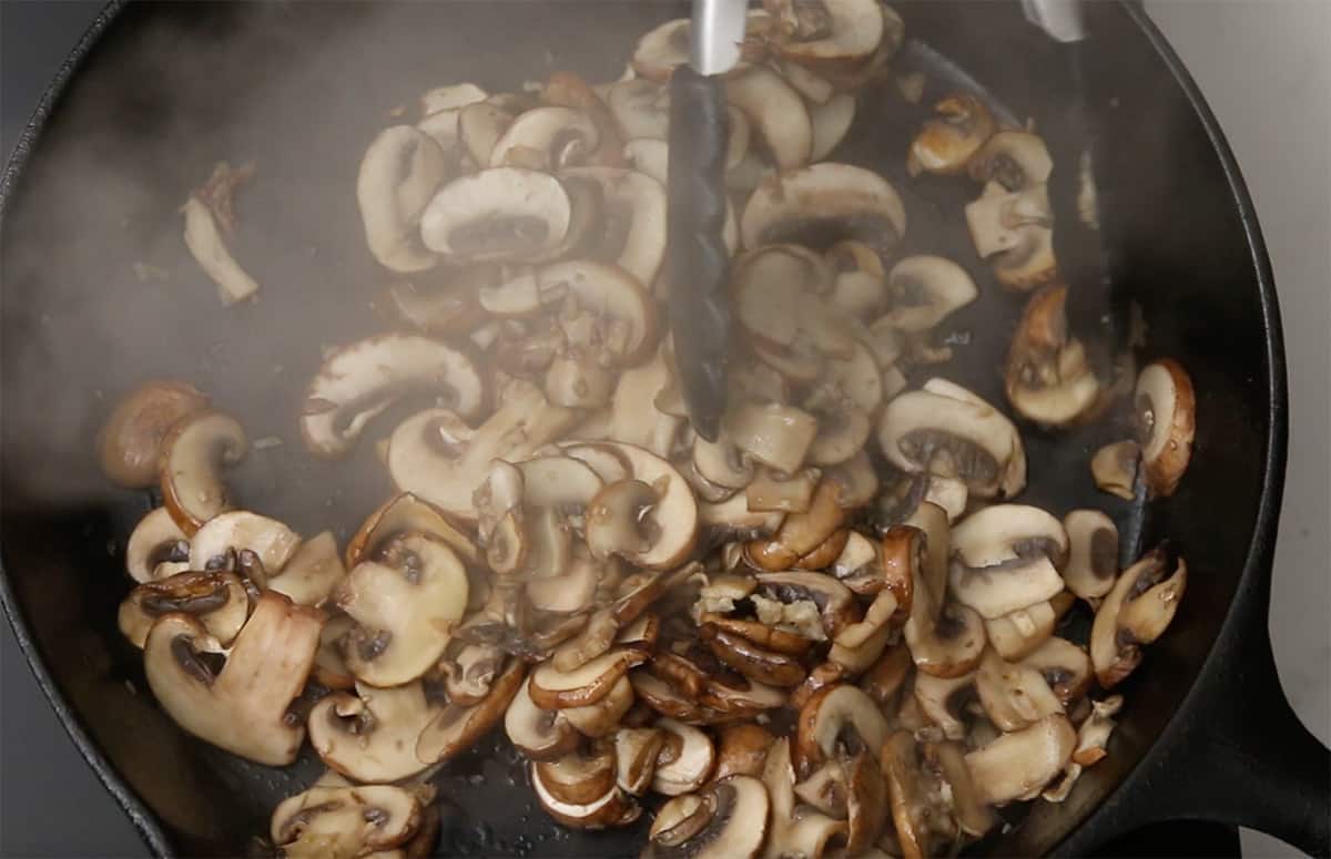 mushrooms cooking in a cast iron skillet