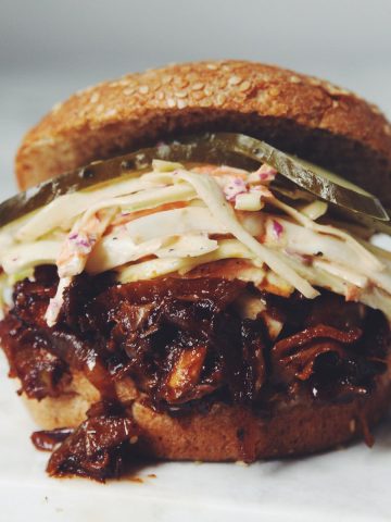 close up of a vegan pulled pork sandwich with coleslaw and pickles
