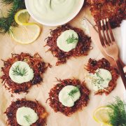 overhead of a platter of vegan latkes garnished with lemon dill sour cream, and fresh dill