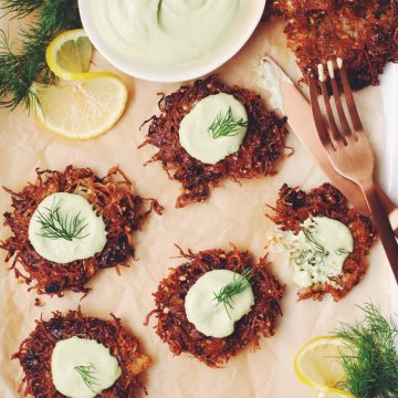 overhead of a platter of vegan latkes garnished with lemon dill sour cream, and fresh dill