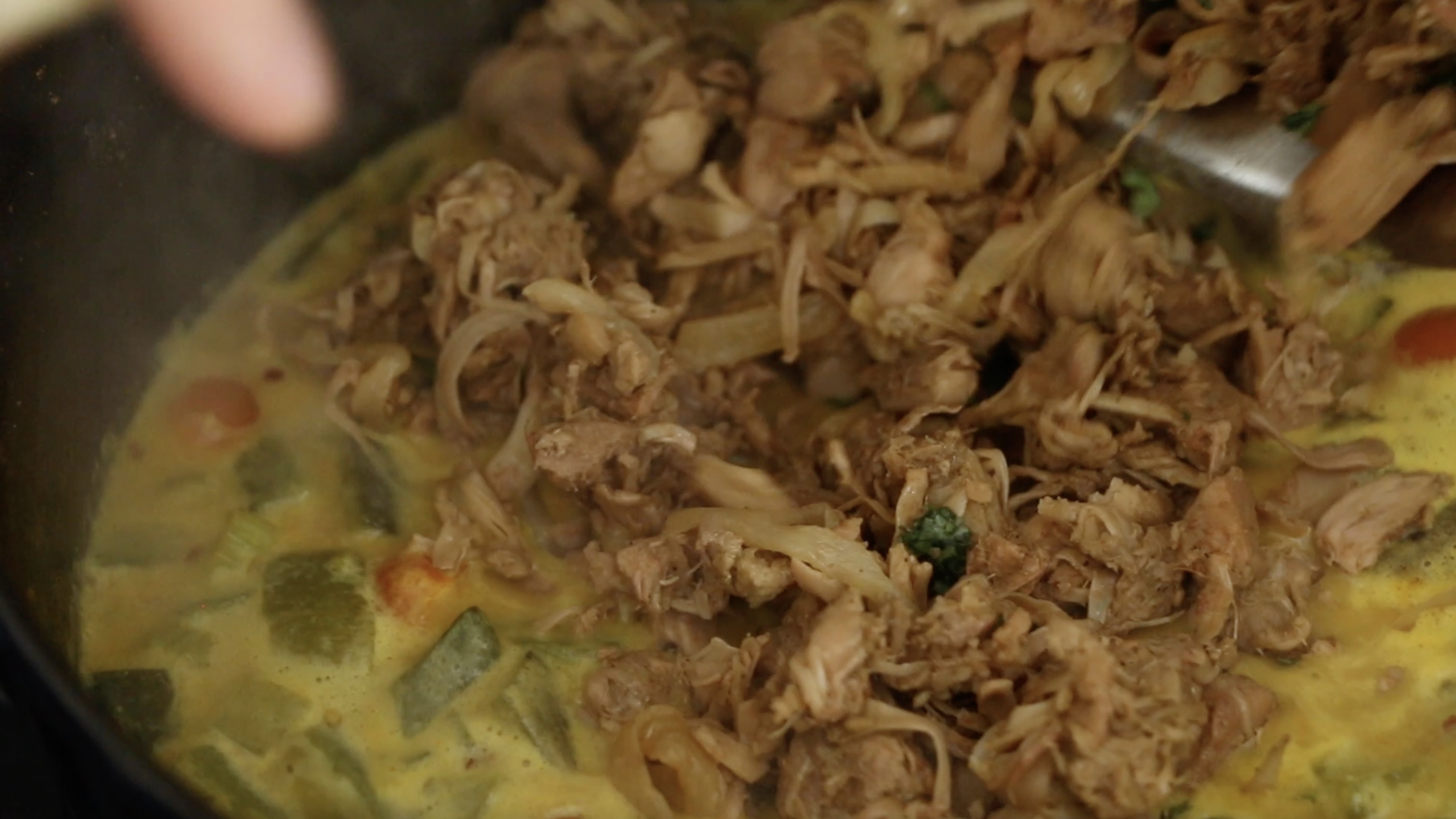 seasoned jackfruit going into pot of vegan laksa