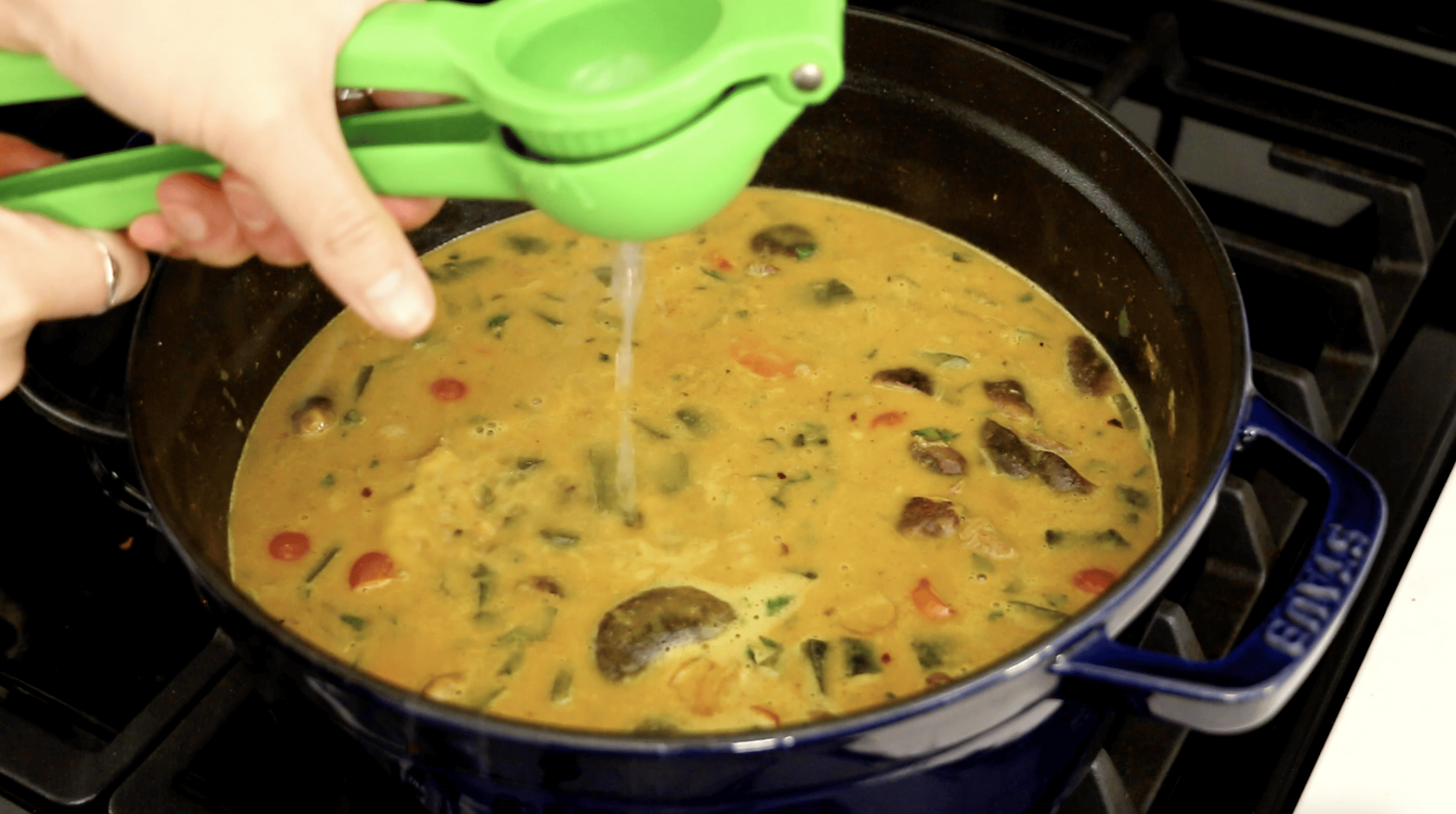 lime juice being added to vegan laksa in pot