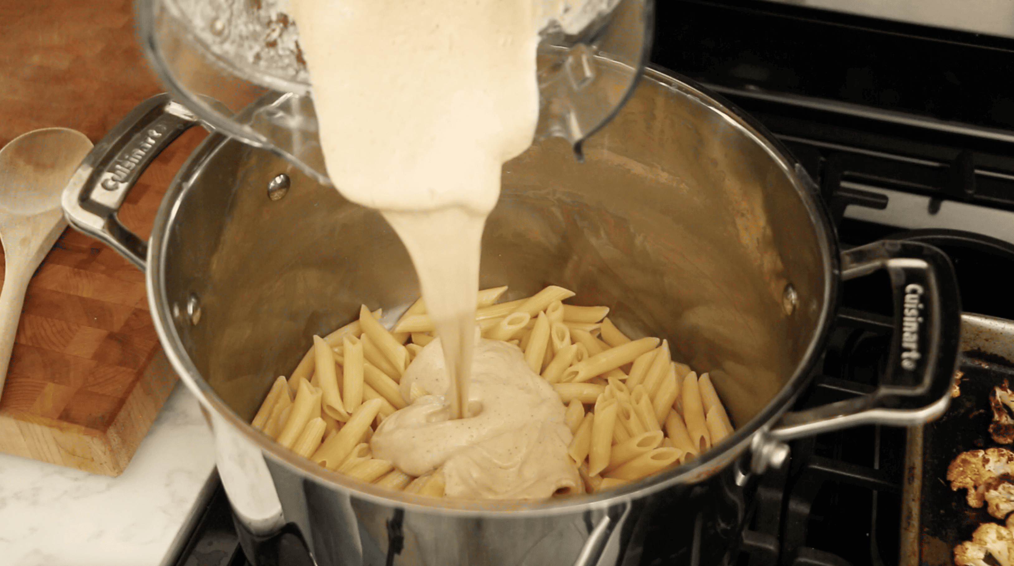cauliflower alfredo sauce being poured onto pasta