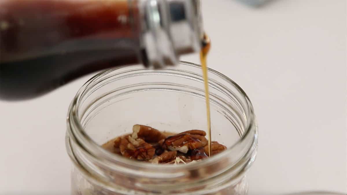overnight oats jar with maple syrup being drizzled in